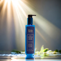 Blue Nectar 24K Gold Body Milk bottle with radiant sunlight beams and water reflections.