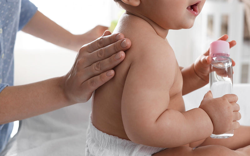 mother is giving massage to baby dry skin with natural baby oil 