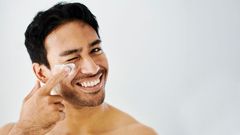 men is applying face cream on his face 