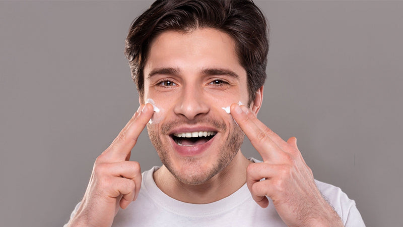 Men is applying anti aging face cream on his cheeks 