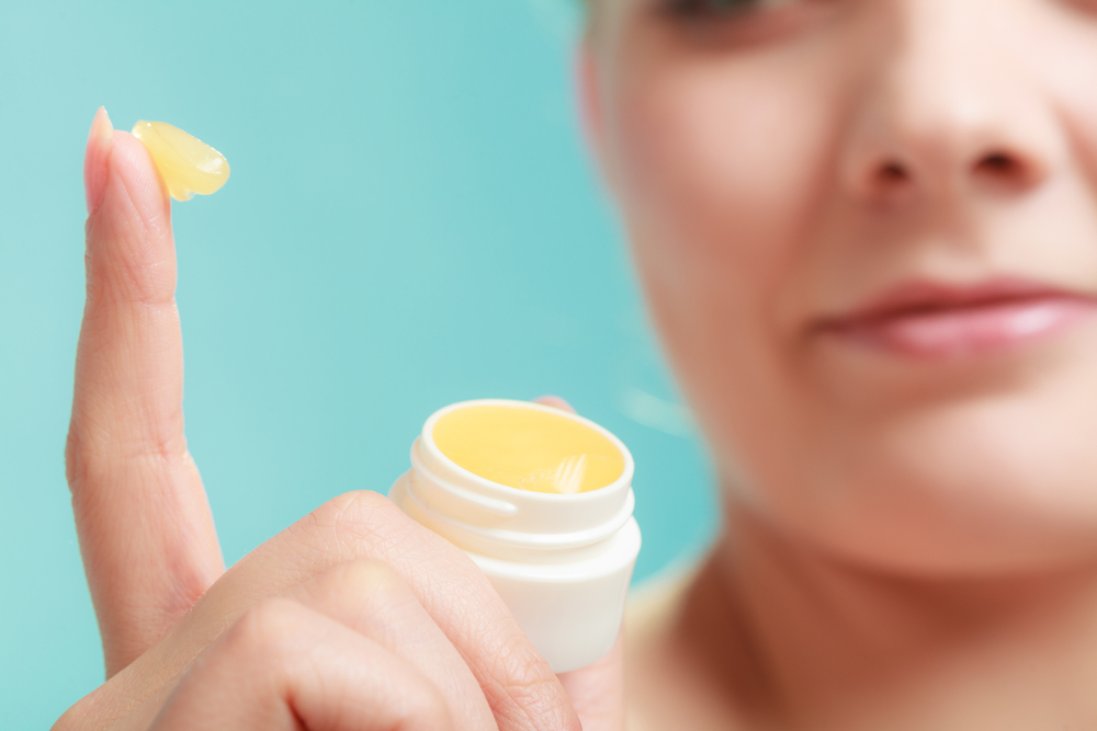 Girl is showing ghee lip balm while pointing out her finger 