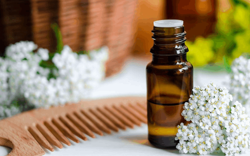 Ayurvedic oil for hairs, comb and flowers are on white table 