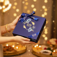 Blue gift box with a decorative bow held by a person against a blurred festive background.