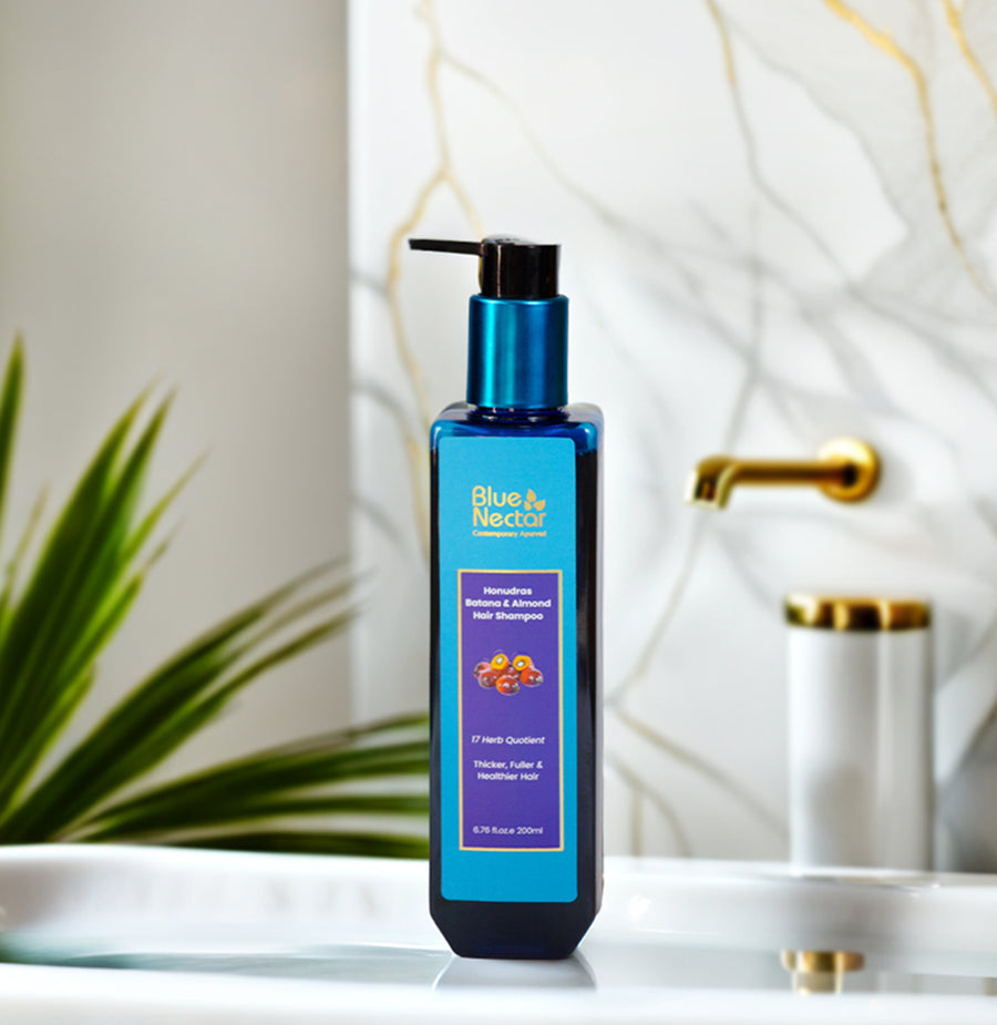 Batana Hair Shampoo placed on a bathroom counter near a gold faucet and green plant, promoting hair strength and scalp health.